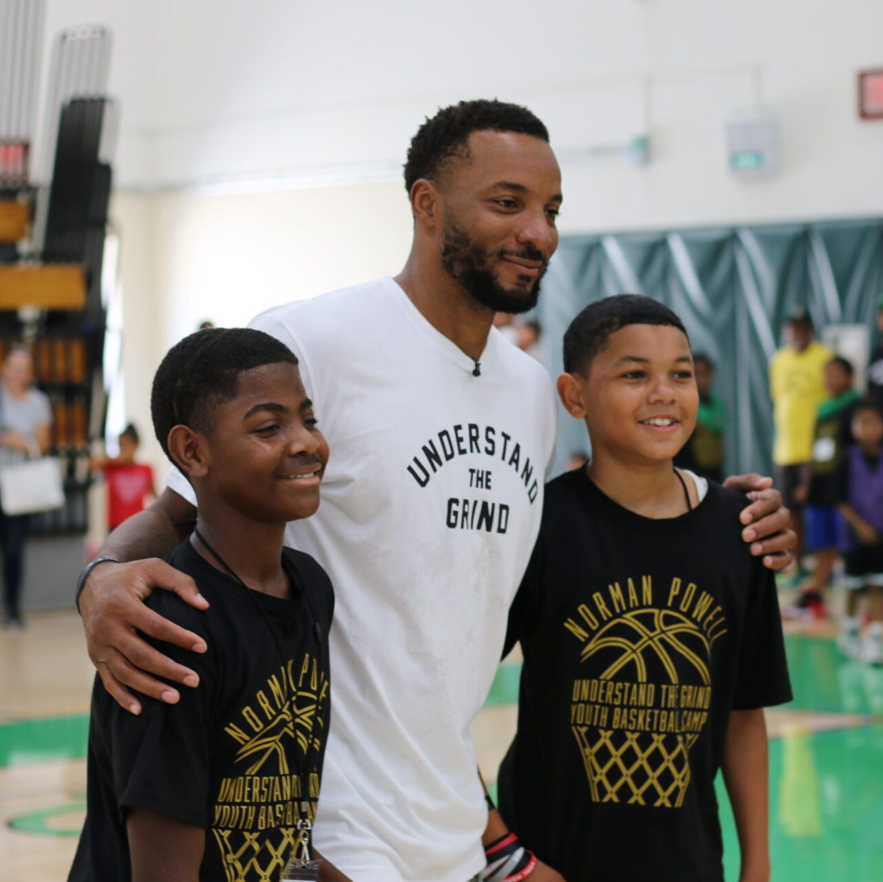 IMG_0077 Norman Powell and 2 youth smiling on the basketball court